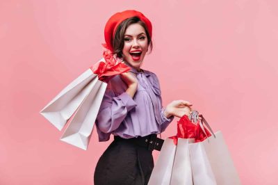 woman-red-hat-black-trousers-light-blouse-laughs-poses-with-packages-after-shopping (1)