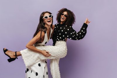 wonderful-woman-black-blouse-trendy-white-pants-laughing-having-fun-with-her-friend-sunglasses-isolated-wall (1) (1)